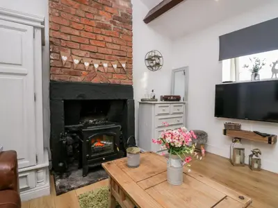 a living room with a fireplace and a table with flowers at High Wreah Bolt Hole in Whitehaven
