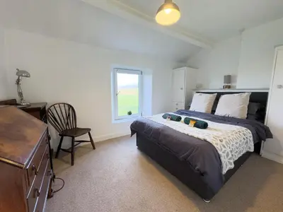 a bedroom with a bed with a desk and a window at Escape to our Cosy Cottage with Log Burner in Drigg, Lake District in Drigg