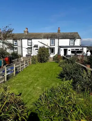 a house with a green yard in front of it at Escape to our Cosy Cottage with Log Burner in Drigg, Lake District in Drigg