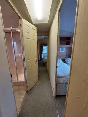 a small room with a bedroom with a bed and an open door at Winnie - Caravan mit Meerblick in Drummore