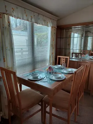 a dining room table with chairs and a large window at Winnie - Caravan mit Meerblick in Drummore