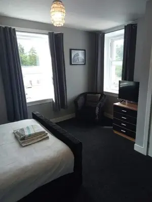 a bedroom with a bed and a television and a chair at Fleet Townhouse in Gatehouse of Fleet