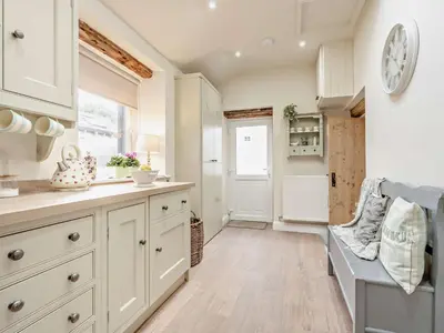 a kitchen with white cabinets and a bench and a window at 2 Bed in Bridekirk 93280 in Bridekirk