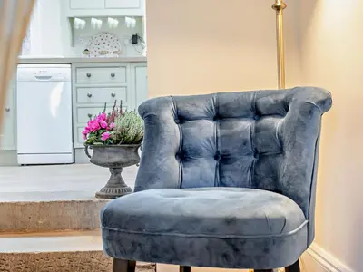 a blue leather chair in a kitchen with a vase of flowers at 2 Bed in Bridekirk 93280 in Bridekirk