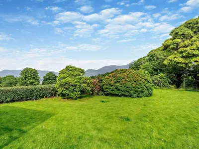 a field of grass with trees and mountains in the background at 3 Bed in Keswick 93202 in Keswick