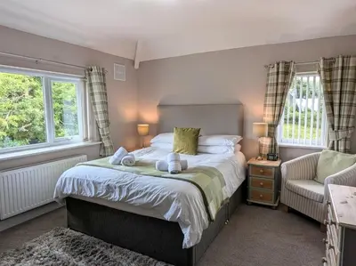 a bedroom with a bed and a chair and two windows at 3 Bed in Keswick 93202 in Keswick
