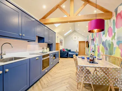 a kitchen with blue cabinets and a dining room with a table at 1 Bed in Lockerbie 93110 in Lockerbie