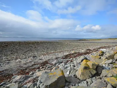 a beach with rocks and the ocean in the background at 3 Bed in Mochrum 87541 in Mochrum