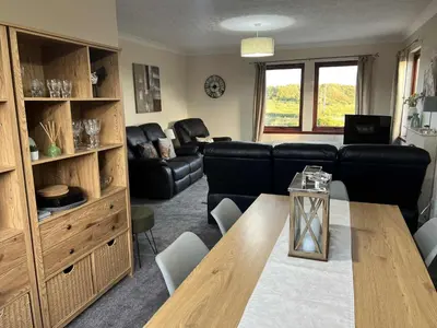 a living room with a black couch and a table at 3 Bed in Mochrum 87541 in Mochrum