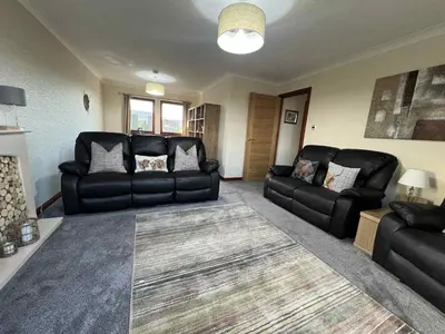 a living room with black leather furniture and a rug at 3 Bed in Mochrum 87541 in Mochrum