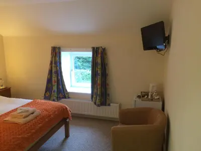 a bedroom with a bed and a chair and a window at The Village Inn in Kirtlebridge
