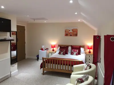 a bedroom with a large bed with red pillows at The Village Inn in Kirtlebridge