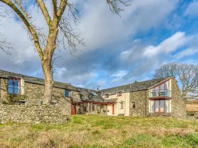 an exterior view of a stone house with a tree at 4 Bed in Broughton Mills 75286 in Seathwaite