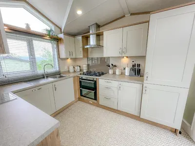 a kitchen with white cabinets and a sink at Serena Holiday Caravan in Bassenthwaite