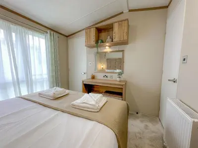 a bedroom with a bed and a sink and a mirror at Serena Holiday Caravan in Bassenthwaite