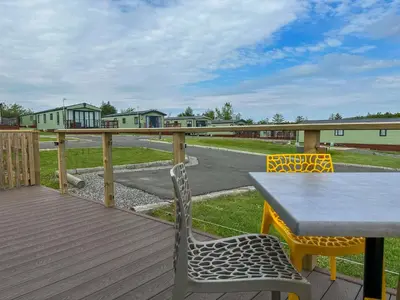 a wooden deck with a table and chairs on it at Serena Holiday Caravan in Bassenthwaite