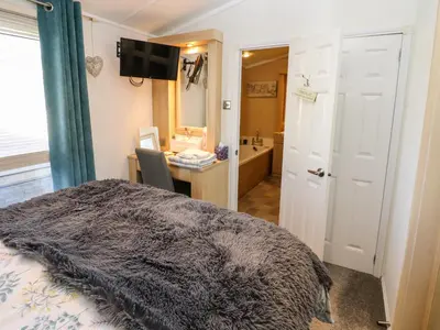 a bedroom with a bed and a desk and a bathroom at A and C Lodge-Plot 21 in Carlisle