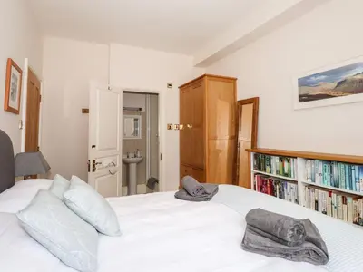 a bedroom with a white bed with a book shelf at Walla Crag, Royal Oak House in Keswick