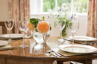 a table with glasses and plates and flowers in a vase at 2 Bed in Eskdale SZ346 in Santon Bridge