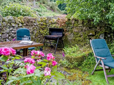 a garden with two chairs and a table and flowers at 4 Bed in Holmrook oc-sz158 in Eskdale