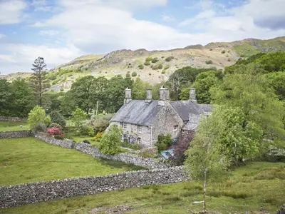 an old house in a field with a stone wall at 4 Bed in Holmrook oc-sz158 in Eskdale