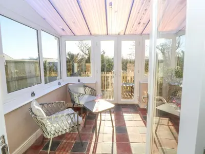 a screened in porch with chairs and windows at Hillside Hideaway in Wigton