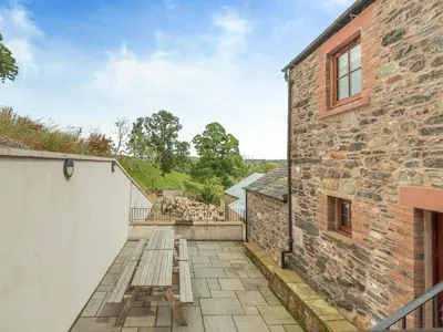 a patio with a wooden bench next to a building at Herdwick House - Uk42805 in Mungrisdale