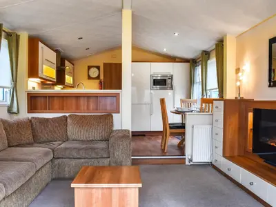 a living room with a couch and a kitchen at Inglenook Lodge in Lamplugh