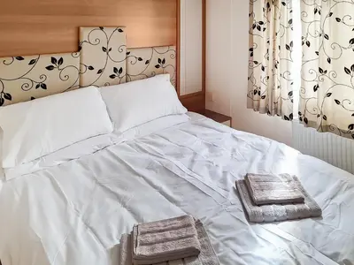a white bed with two towels on top of it at Inglenook Lodge in Lamplugh