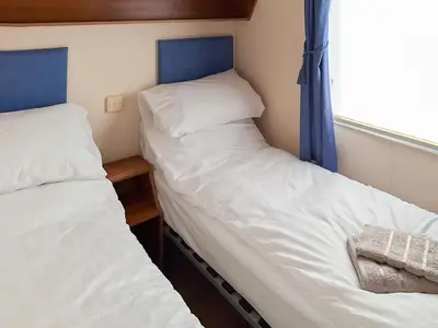 two beds in a small room with a window at Inglenook Lodge in Lamplugh