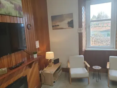 a living room with a television and a table and chairs at Luxury 1BR Flat Central Dumfries Self Check-in, Parking, Wi-Fi in Dumfries