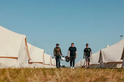 a group of men walking through a row of tents at Duke Travel Official TT Glamping - Douglas in Kirk Braddon