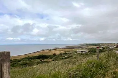 a grassy hill with the ocean in the background at ERIN NEAMH - Magnificent sea views cosy cottage in Cumbria in Harrington