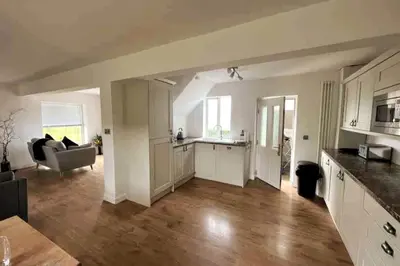 a kitchen and living room with a couch and a table at ERIN NEAMH - Magnificent sea views cosy cottage in Cumbria in Harrington