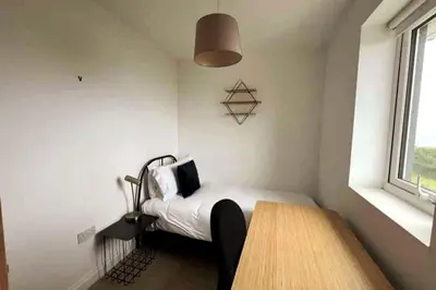 a bedroom with a bed and a wooden table at ERIN NEAMH - Magnificent sea views cosy cottage in Cumbria in Harrington