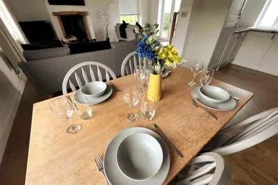 a wooden table with plates and wine glasses on it at ERIN NEAMH - Magnificent sea views cosy cottage in Cumbria in Harrington