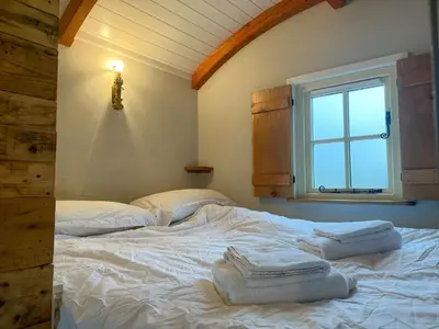 a bedroom with a white bed with a window at Shepherds Hut at Maes Uldale stunning fell views and next door to popular cafe for sweet treats in Uldale