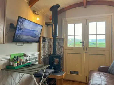 a living room with a wood stove and a door at Shepherds Hut at Maes Uldale stunning fell views and next door to popular cafe for sweet treats in Uldale