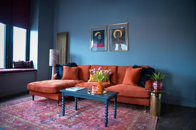 a living room with a orange couch and a table at The Bank - Rooms & Apartments by Coorie Doon Stays in Troon