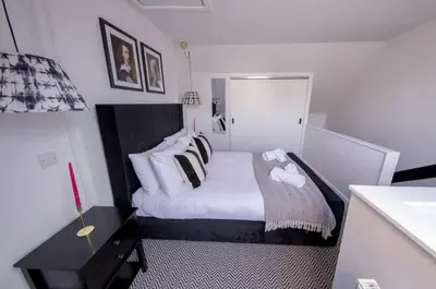 a small bedroom with a bed with white sheets and pillows at The Bradan - Troon - Coorie Doon Stays in Troon