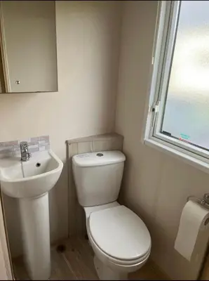 a bathroom with a toilet and a sink and a window at GDs Luxury Caravan Hire Turnberry Holiday Park in Turnberry