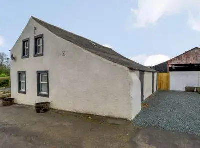 a white building with a garage and a barn at Barncroft: Dogs welcome, dog care services offered in Cockermouth
