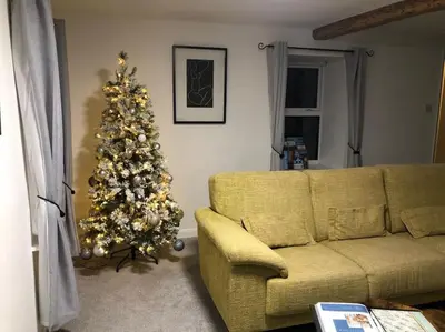a living room with a christmas tree and a yellow couch at Barncroft: Dogs welcome, dog care services offered in Cockermouth