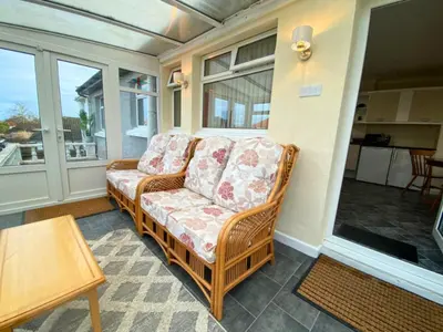 a wicker couch sitting on a screened in porch at 17 The Park in Onchan
