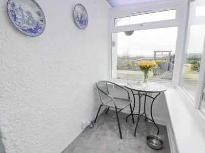 a dining room with a table and chairs and plates on the wall at Rosalin Cottage in Irvine