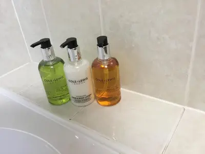 three bottles of soap andodorizers sitting on a sink at Acorn Apartment 1 in Keswick