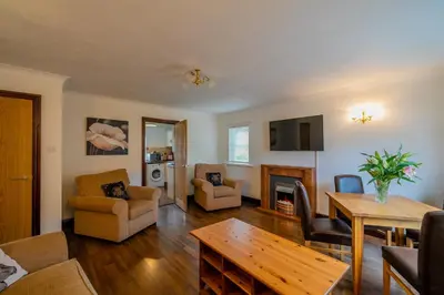 a living room with a table and a fireplace at Acorn Apartment 1 in Keswick