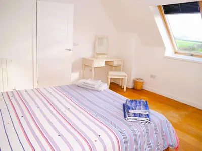 a bedroom with a bed and a desk and a window at The Longhouse in Castle Douglas