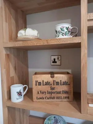 a wooden shelf with cups and a box on it at The Mad Hatter's Shepherd's Hut in Carlisle