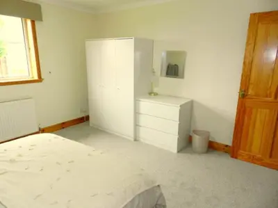 a white bedroom with a bed and a dresser at Annexe Meadowbank Dumfries in Dumfries